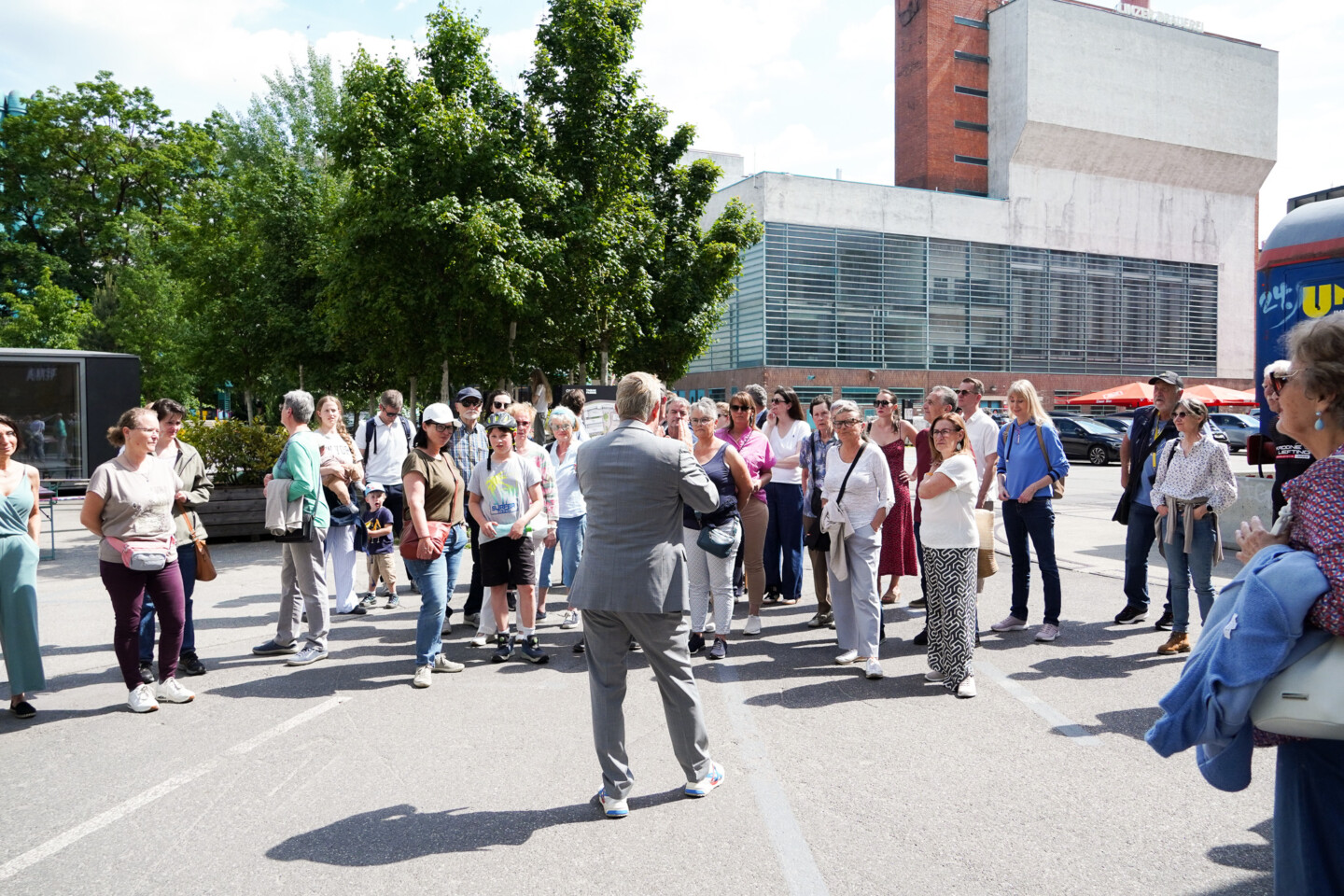 Ein Mitarbeiter der Tabakfabrik Linz führt beim Open Day 2026 eine große interessierte Gruppe durch die Tabakfabrik Linz, bei sonnigem Wetter.